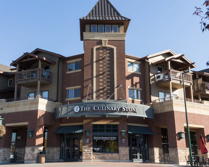 The Culinary Stone storefront in a multi-story brick building with a tower, arched balconies, and a large sign above the entrance.